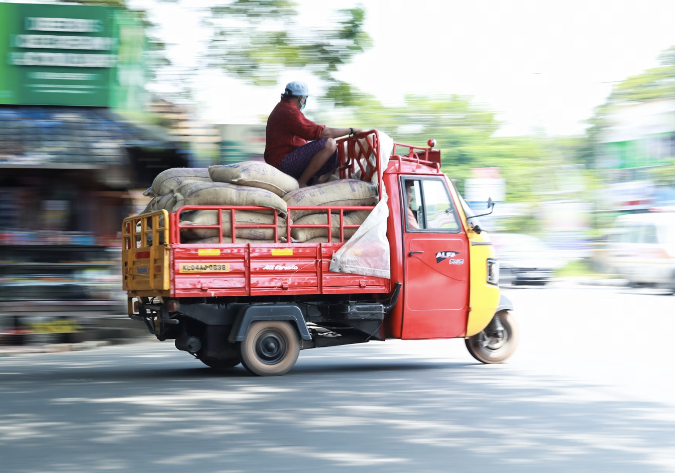 Three-wheeler truck carrying stacked coffee sacks through town